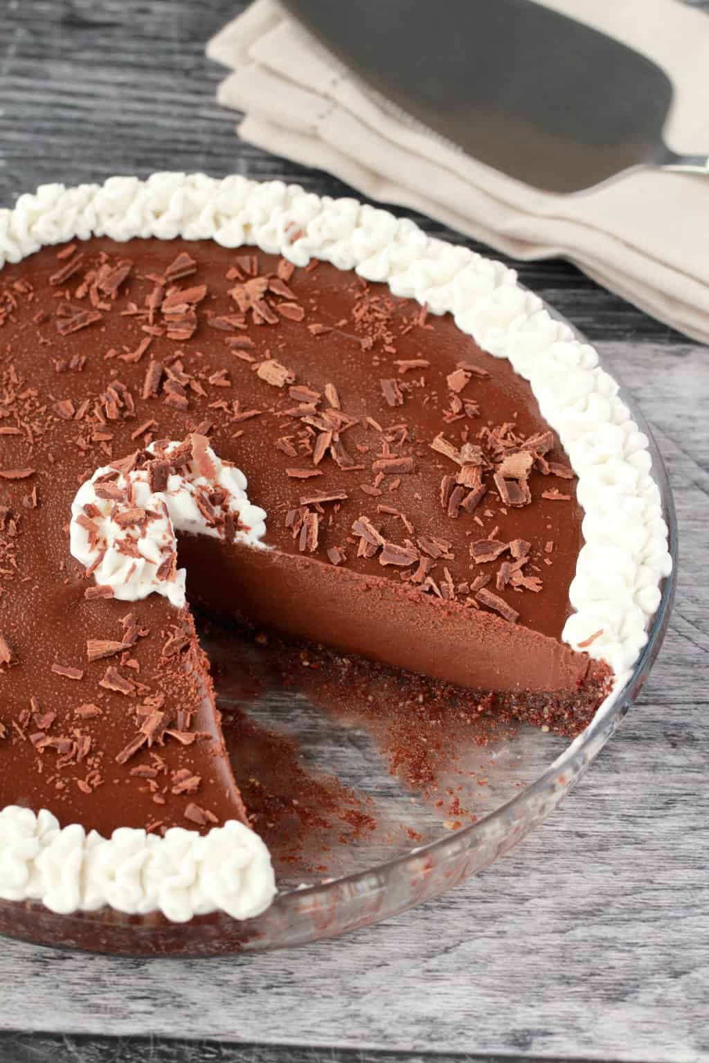 Tarte au chocolat végétalienne dans un plat en verre avec une tranche découpée. 