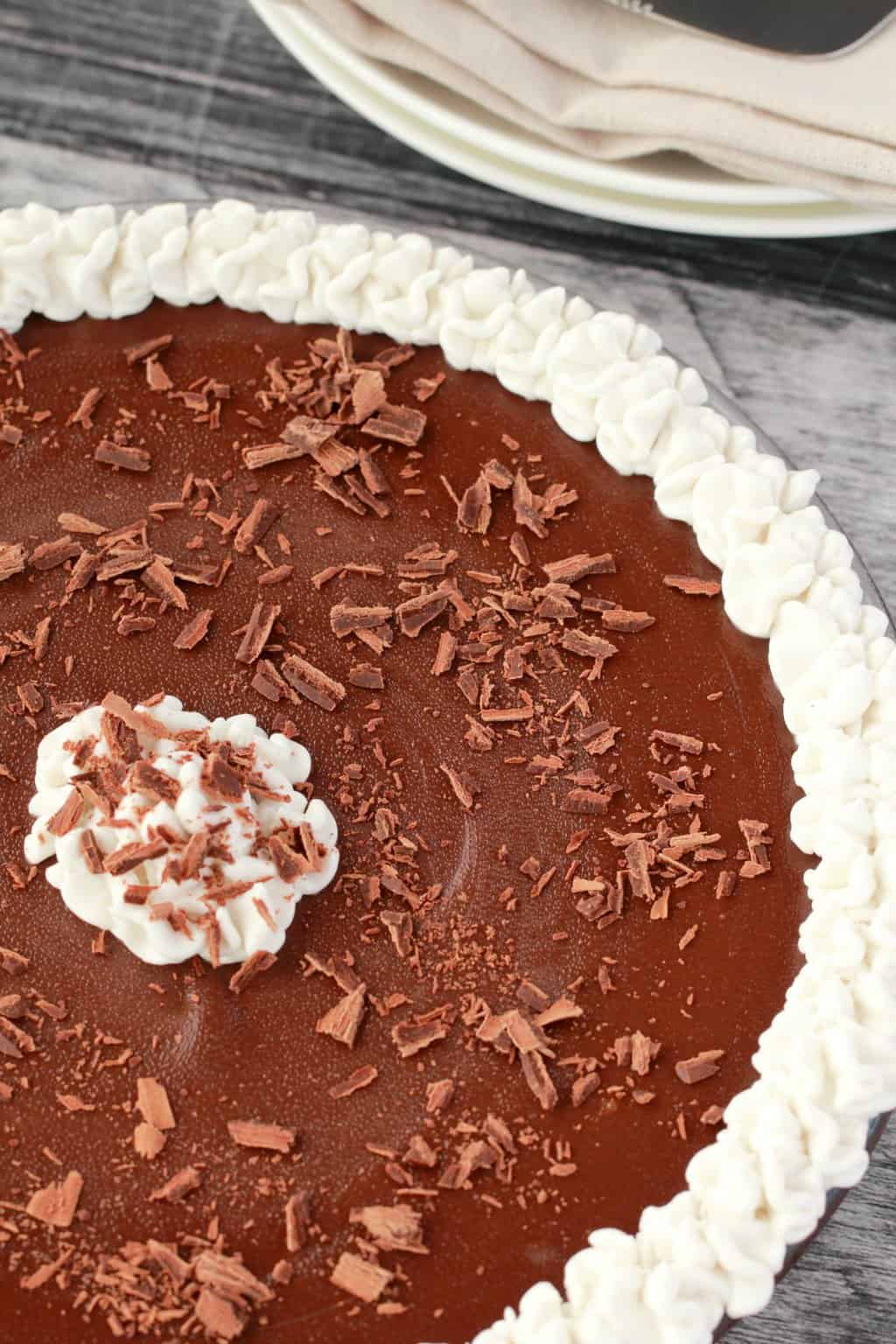Tarte au chocolat végétalienne avec crème de noix de coco fouettée et flocons de chocolat dans un plat en verre. 