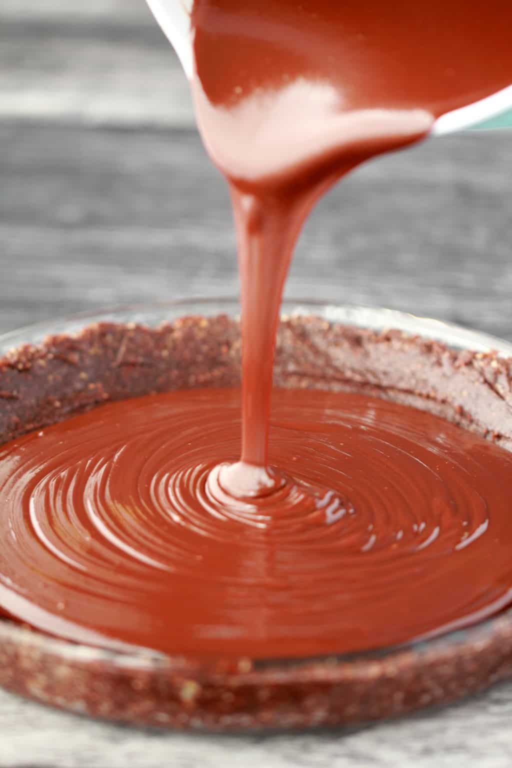 Ganache au chocolat végétalien coulant sur une croûte à tarte. 