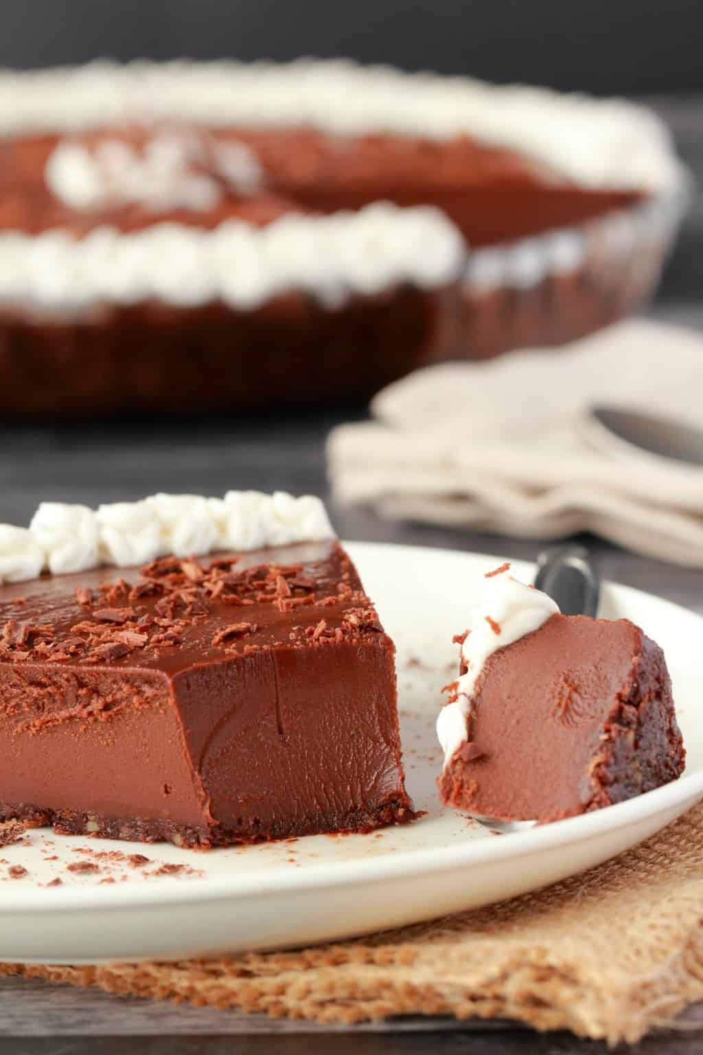 Tranche de tarte au chocolat végétalien sur une plaque blanche avec une fourchette. 