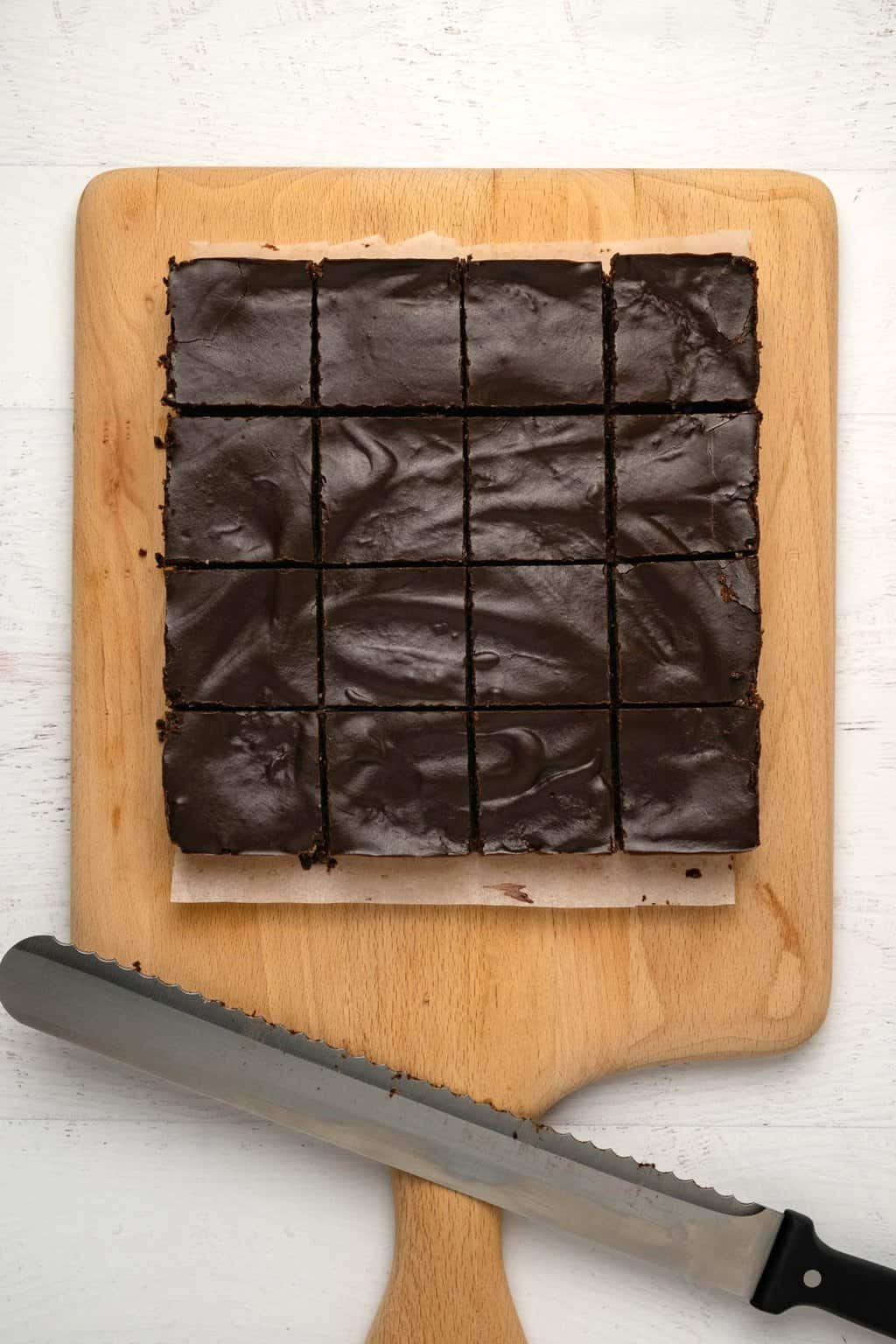 Brownies végétaliens crus coupés en carrés sur une planche de bois.