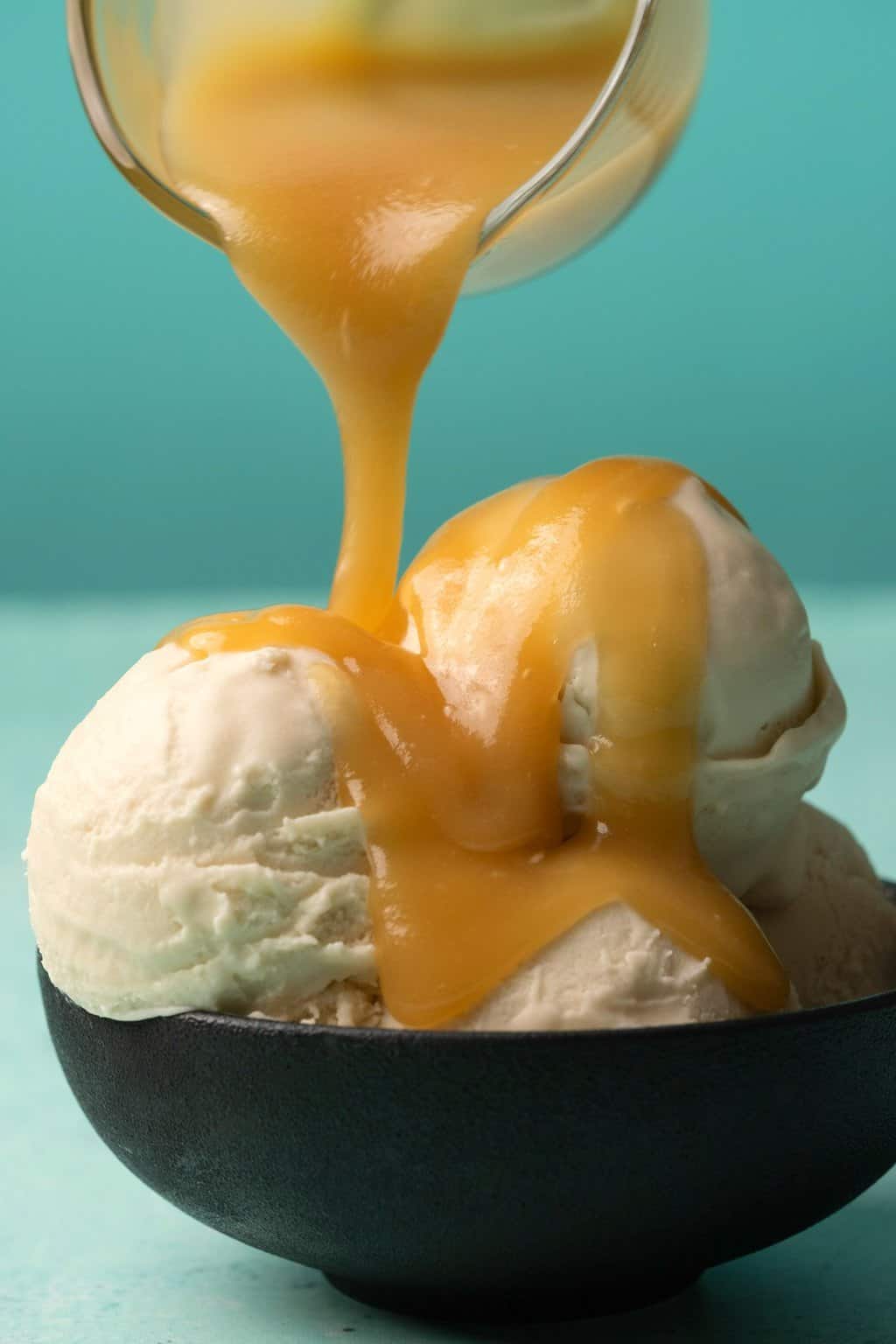 Sauce au caramel végétalienne versant sur de la glace à la vanille.