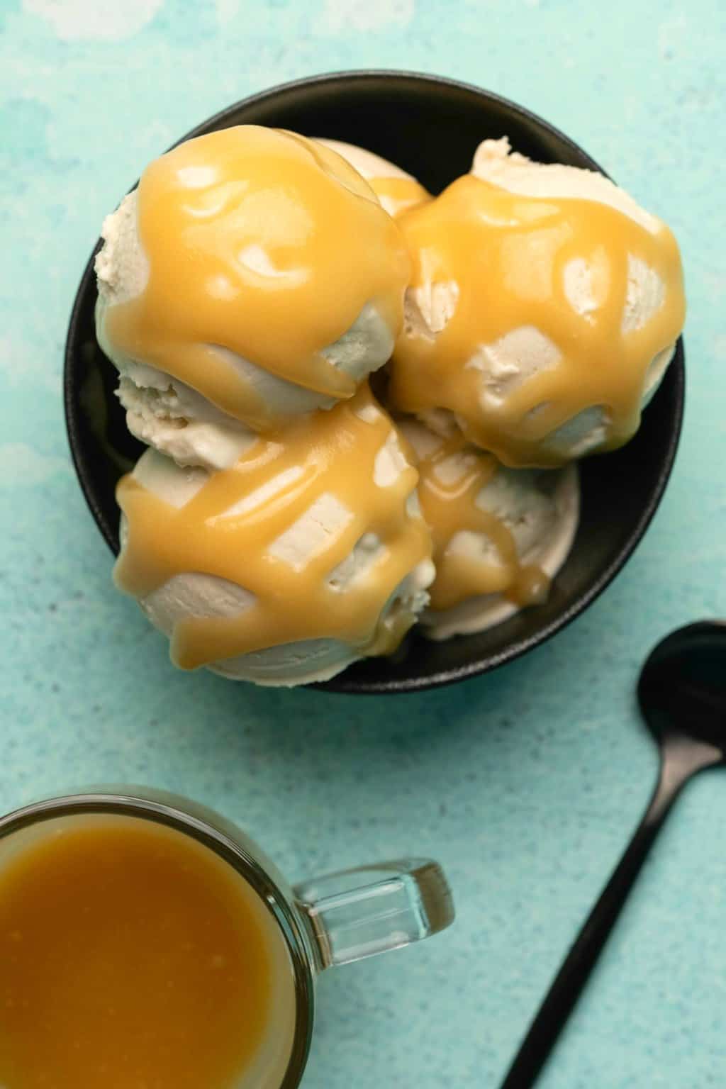 Sauce végétalienne au caramel arrosée de glace à la vanille dans un bol noir.