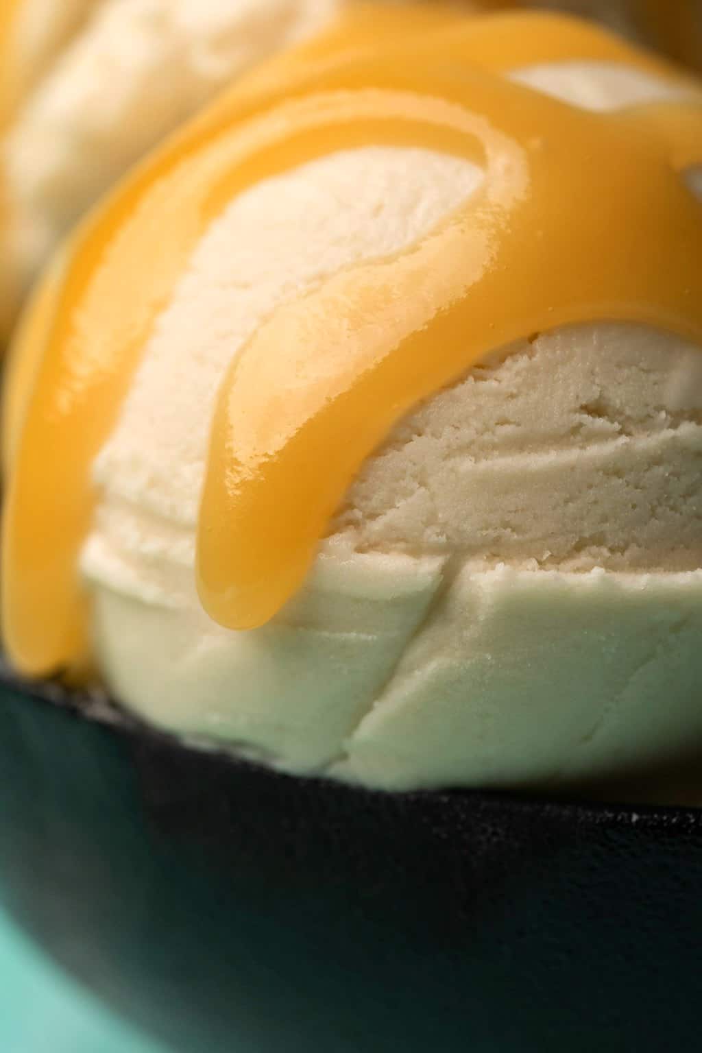 Sauce végétalienne au caramel arrosée de glace à la vanille dans un bol noir.