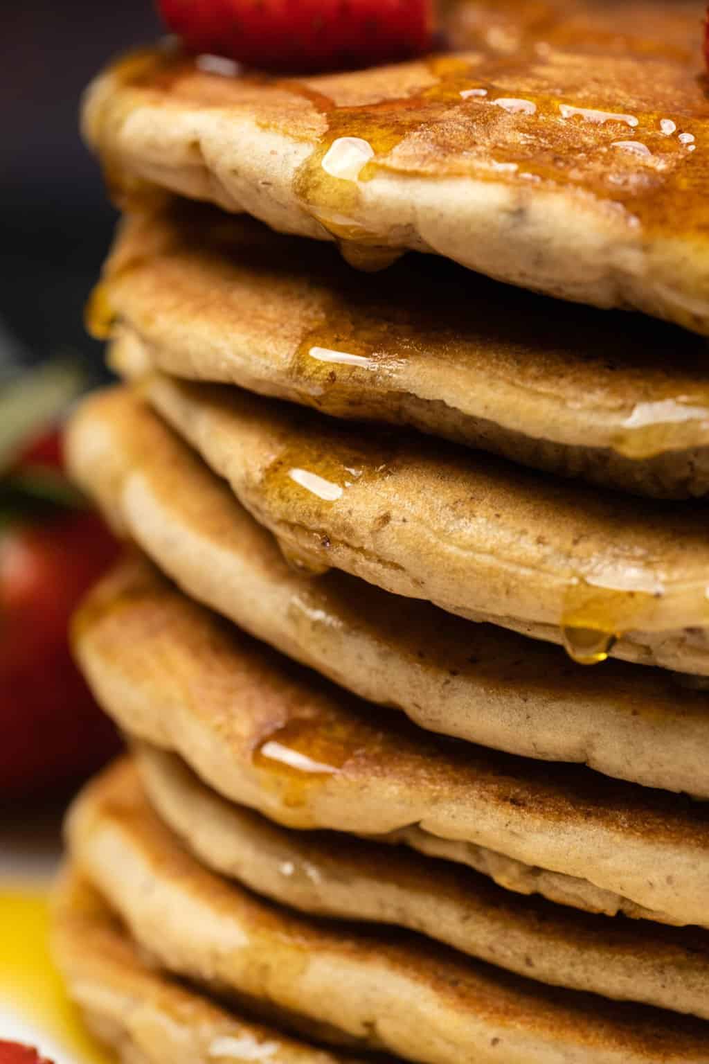 Crêpes protéinées végétaliennes arrosées de sirop sur une plaque blanche.