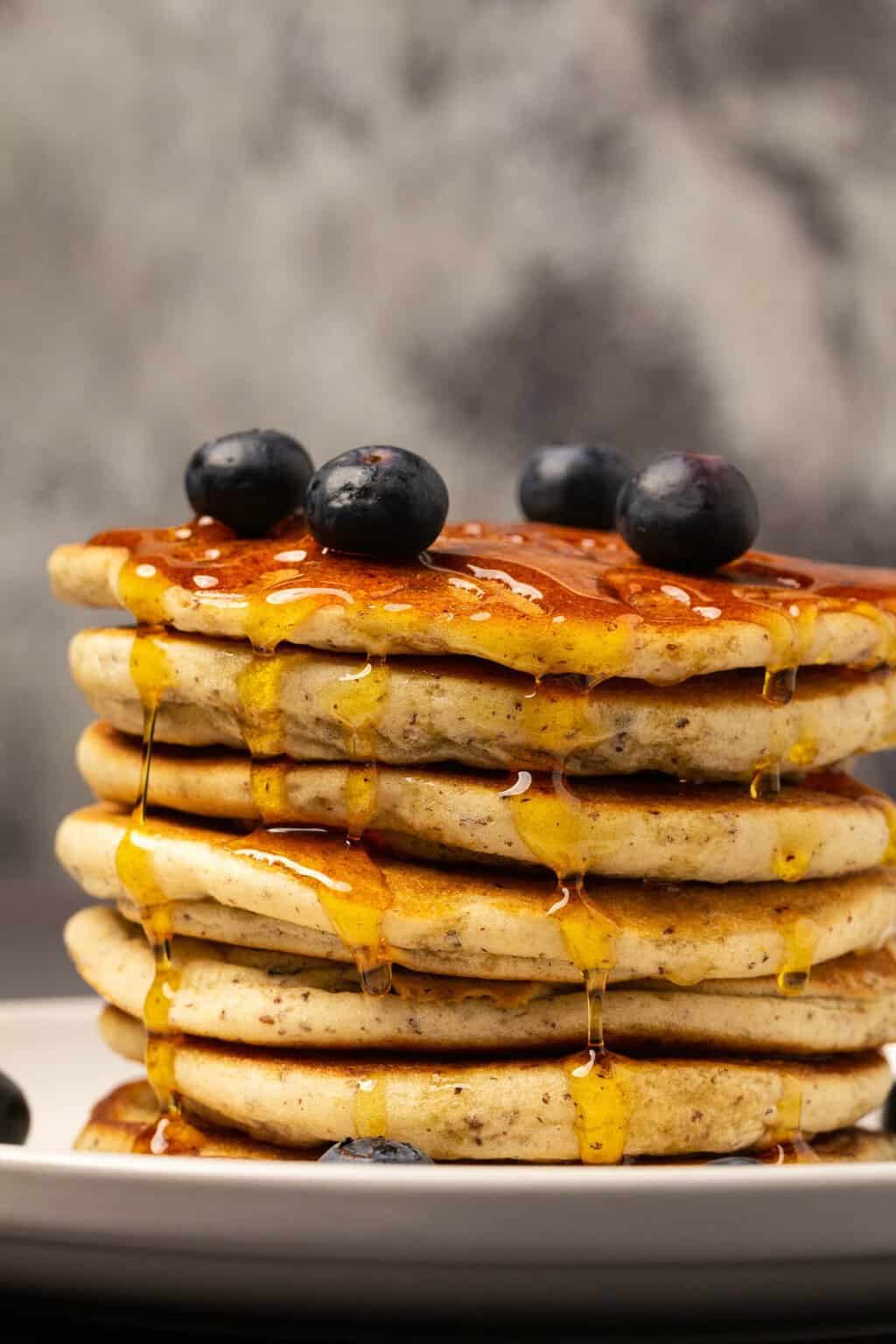 Une pile de crêpes végétaliennes sans gluten avec du sirop et des bleuets. 