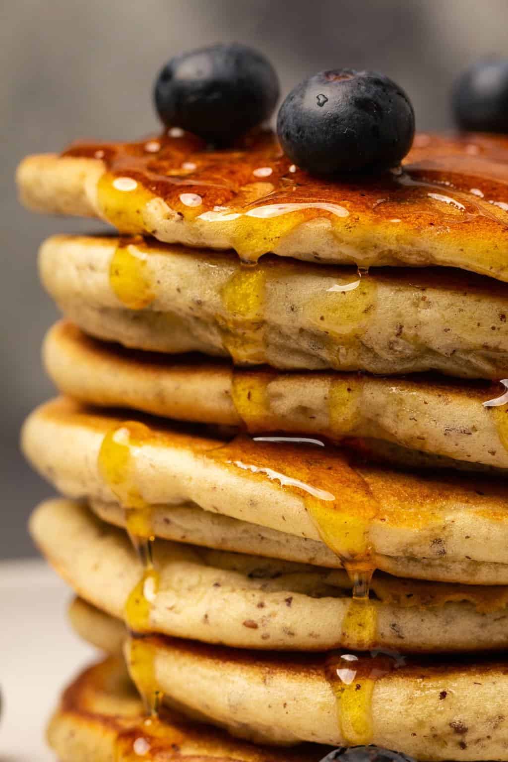 Une pile de crêpes végétaliennes sans gluten arrosées de sirop et garnies de bleuets frais. 