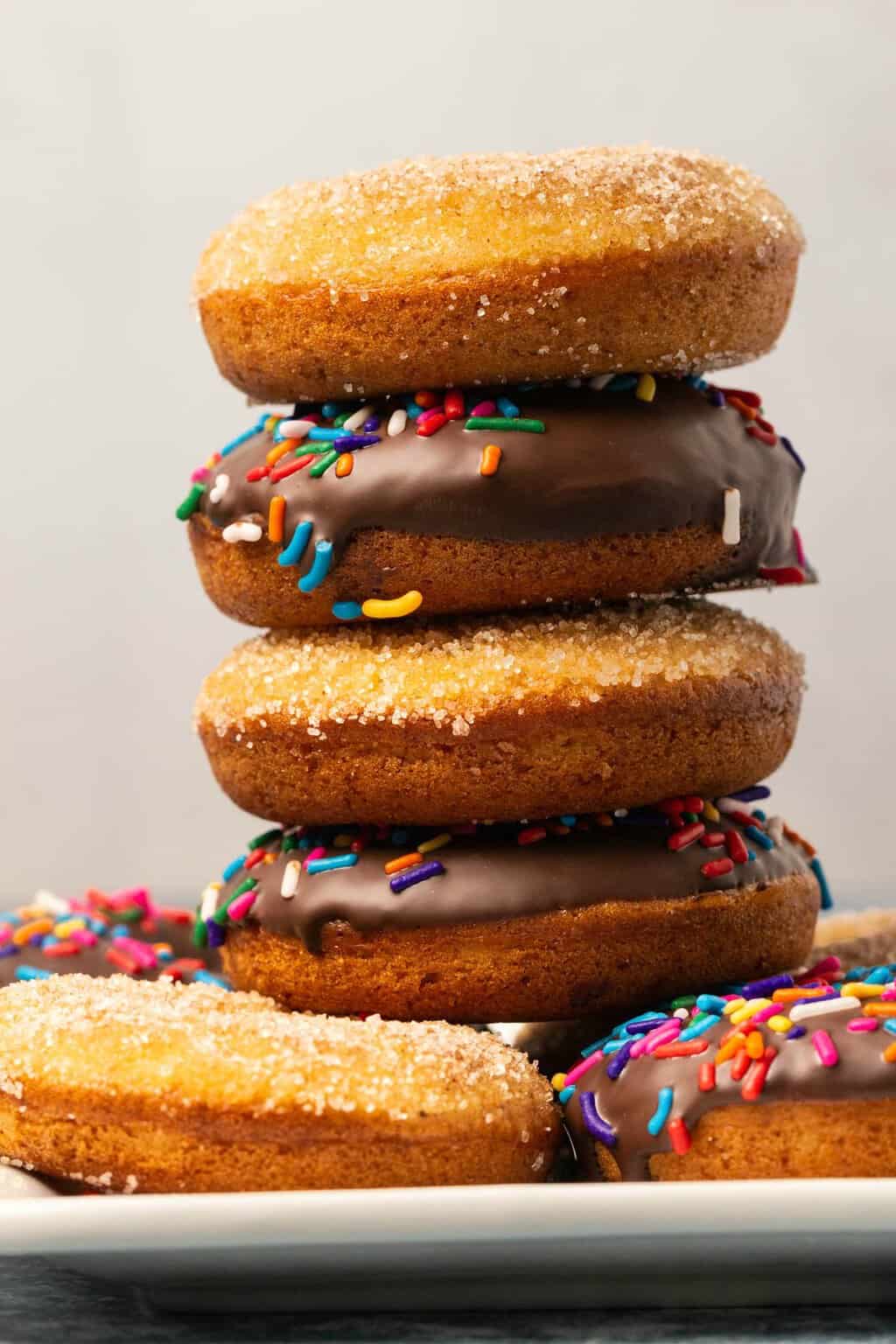 Beignets végétaliens avec garniture au chocolat ou sucre à la cannelle sur une plaque blanche.