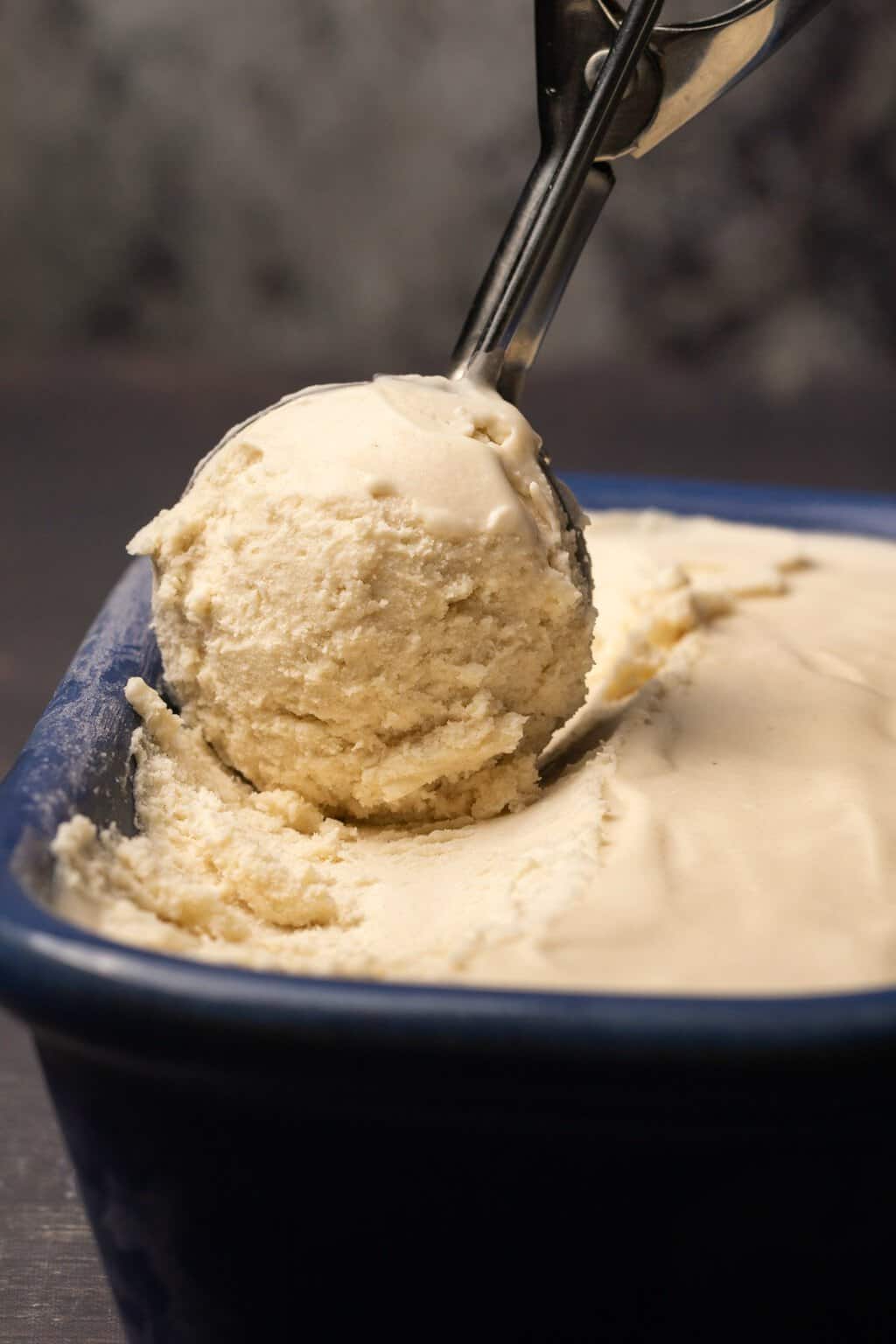 Crème glacée végétalienne dans un plat en céramique bleue avec une cuillère à crème glacée. 