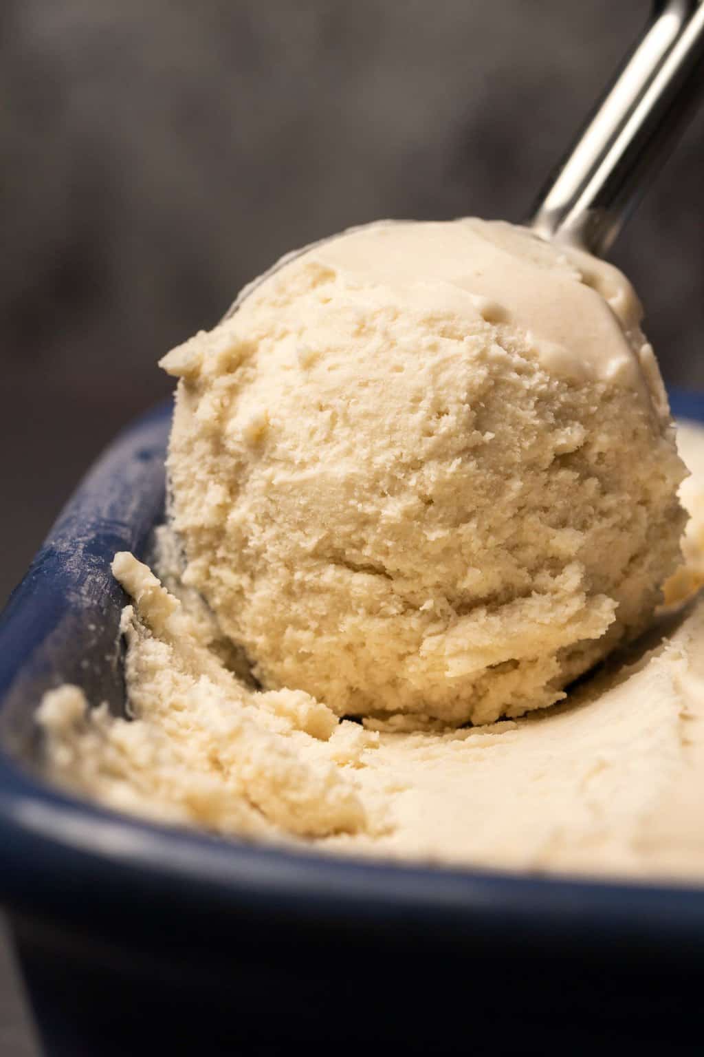 Glace végétalienne dans un moule à pain en céramique bleu avec une cuillère à crème glacée. 