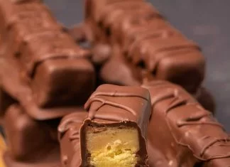 Vegan Twix – Loving It Vegan Twix bars végétaliens empilés sur une planche de bois.