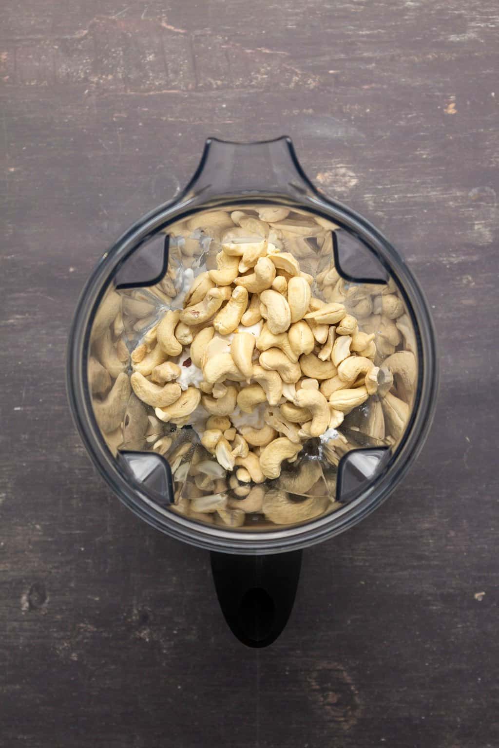Noix de cajou et crème de noix de coco dans un bol mixeur.