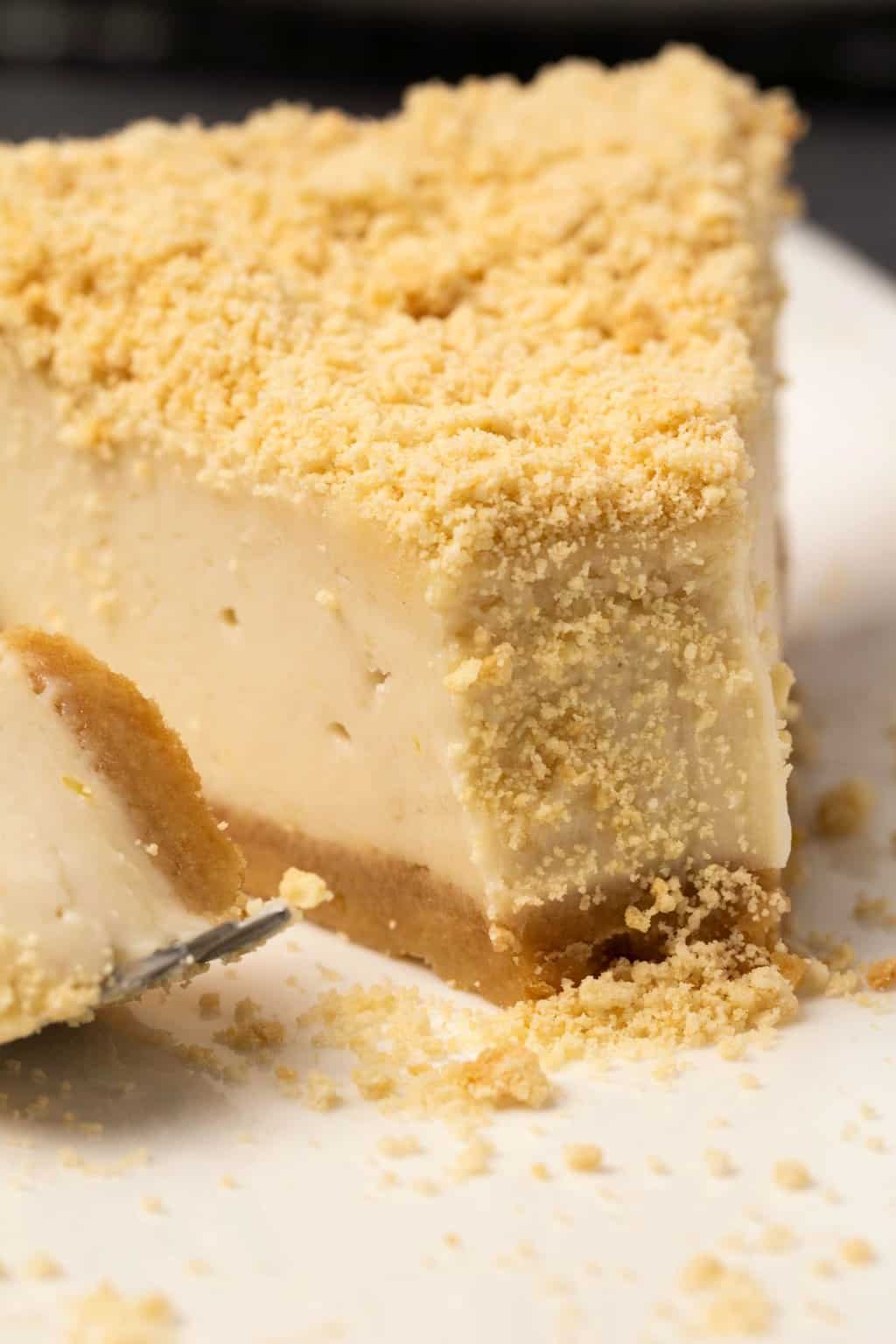 Tranche de cheesecake au four sans produits laitiers sur une plaque blanche avec une fourchette à gâteau.