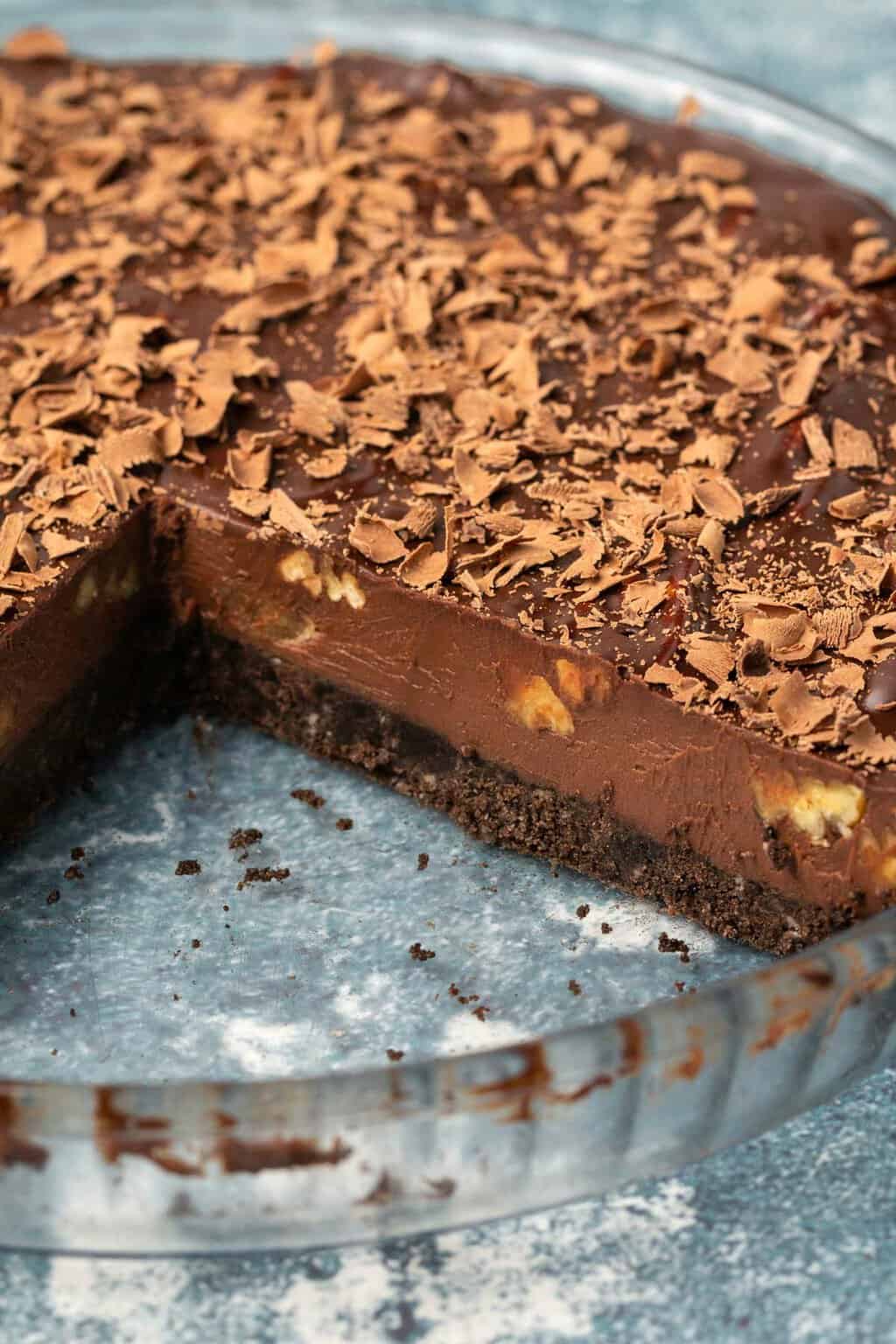 Tarte au chocolat végétalienne dans un plat à tarte en verre avec une tranche retirée.