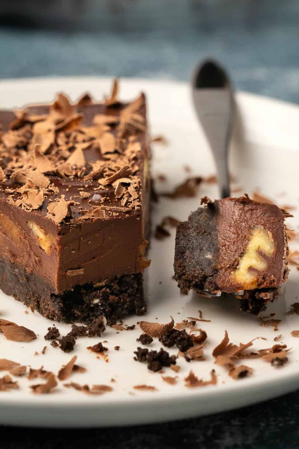 Tranche de tarte au chocolat végétalien sur une plaque blanche avec une fourchette.
