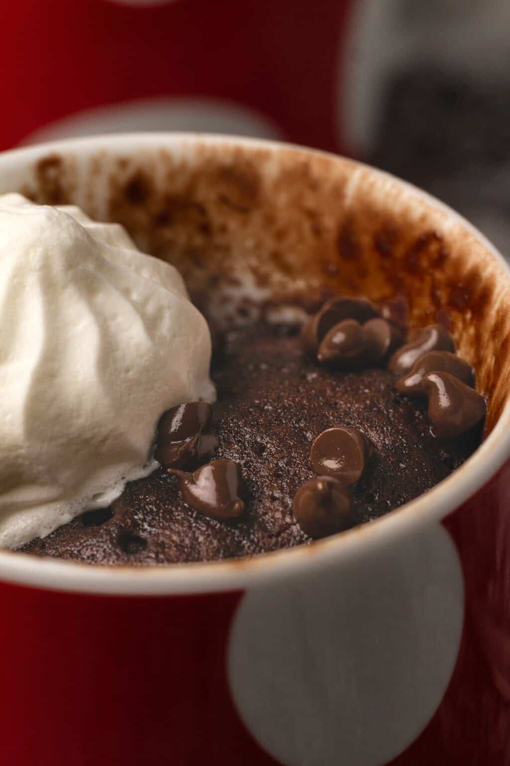 Gâteau mug végétalien garni de pépites de chocolat et de crème végétalienne. 