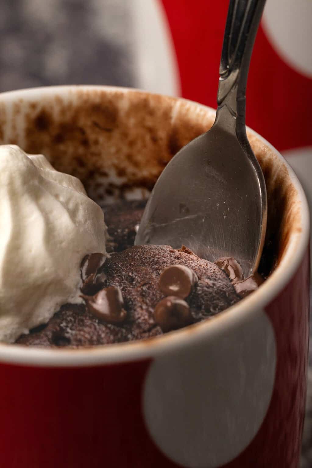 Gâteau mug végétalien dans une tasse rouge et blanche avec une cuillère. 