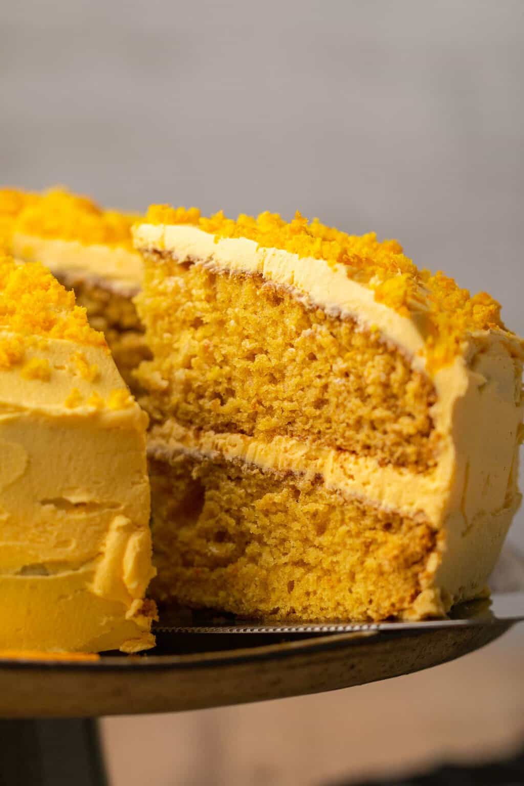 Gâteau orange végétalien en tranches avec un poussoir à gâteau. 
