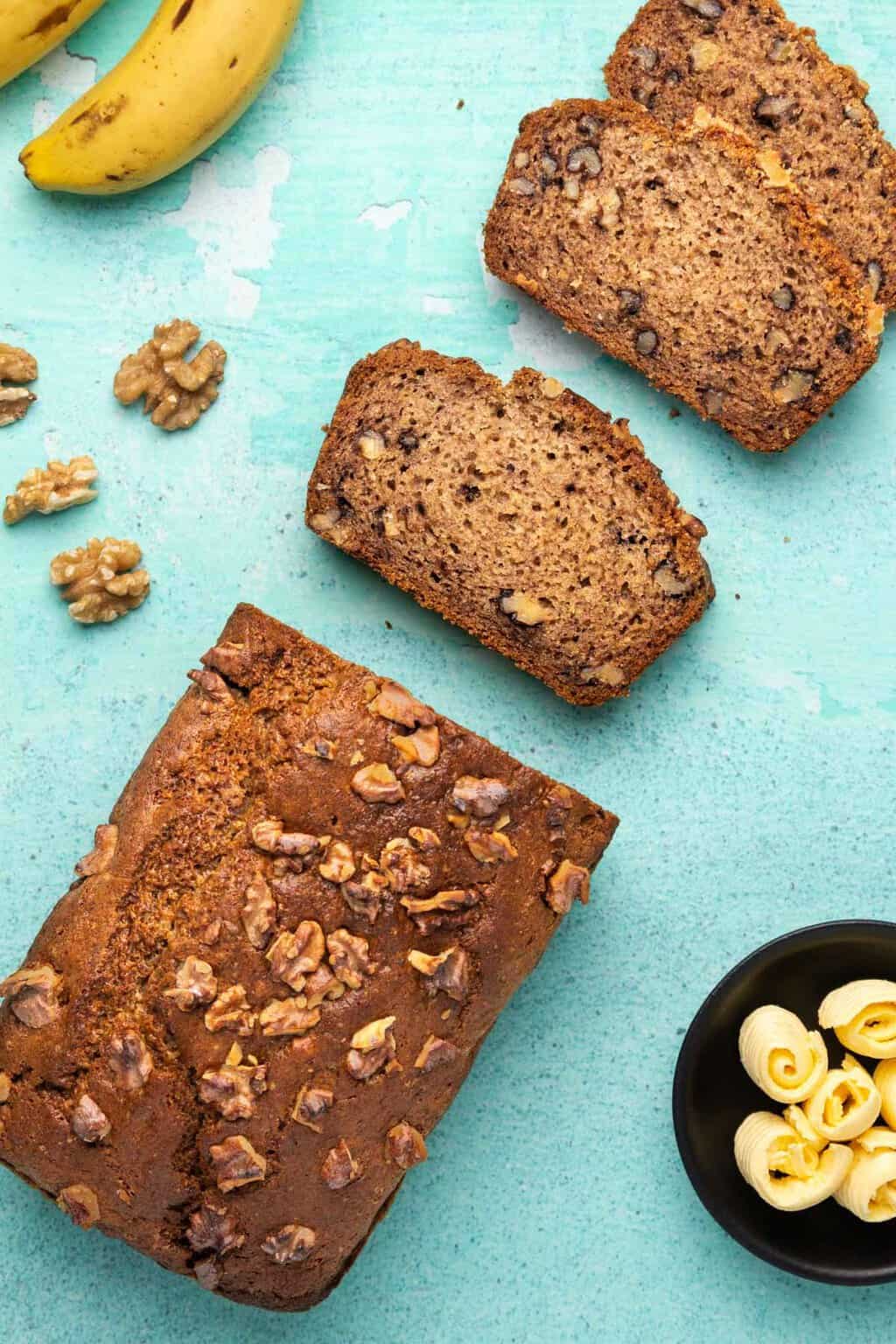 Une miche de pain aux bananes végétalien sans gluten avec plusieurs tranches coupées.