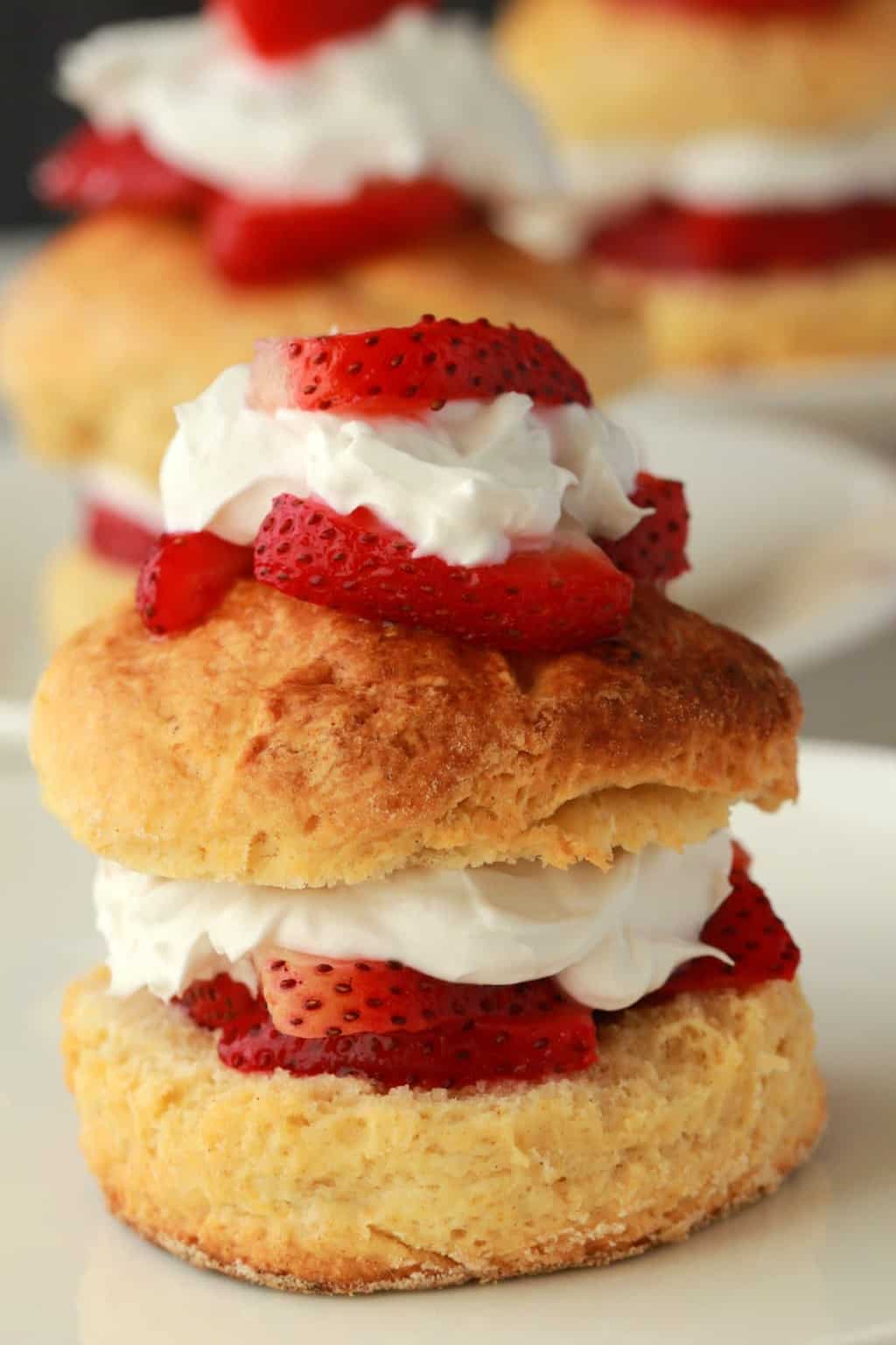 Sablé aux fraises végétalien garni de crème fouettée et de fraises sur une plaque blanche. 