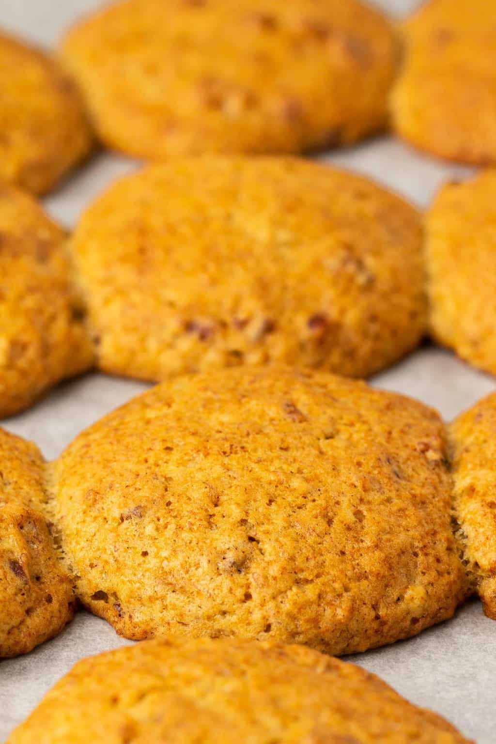 Biscuits végétaliens aux bananes fraîchement cuits sur une plaque à pâtisserie tapissée de papier sulfurisé. 