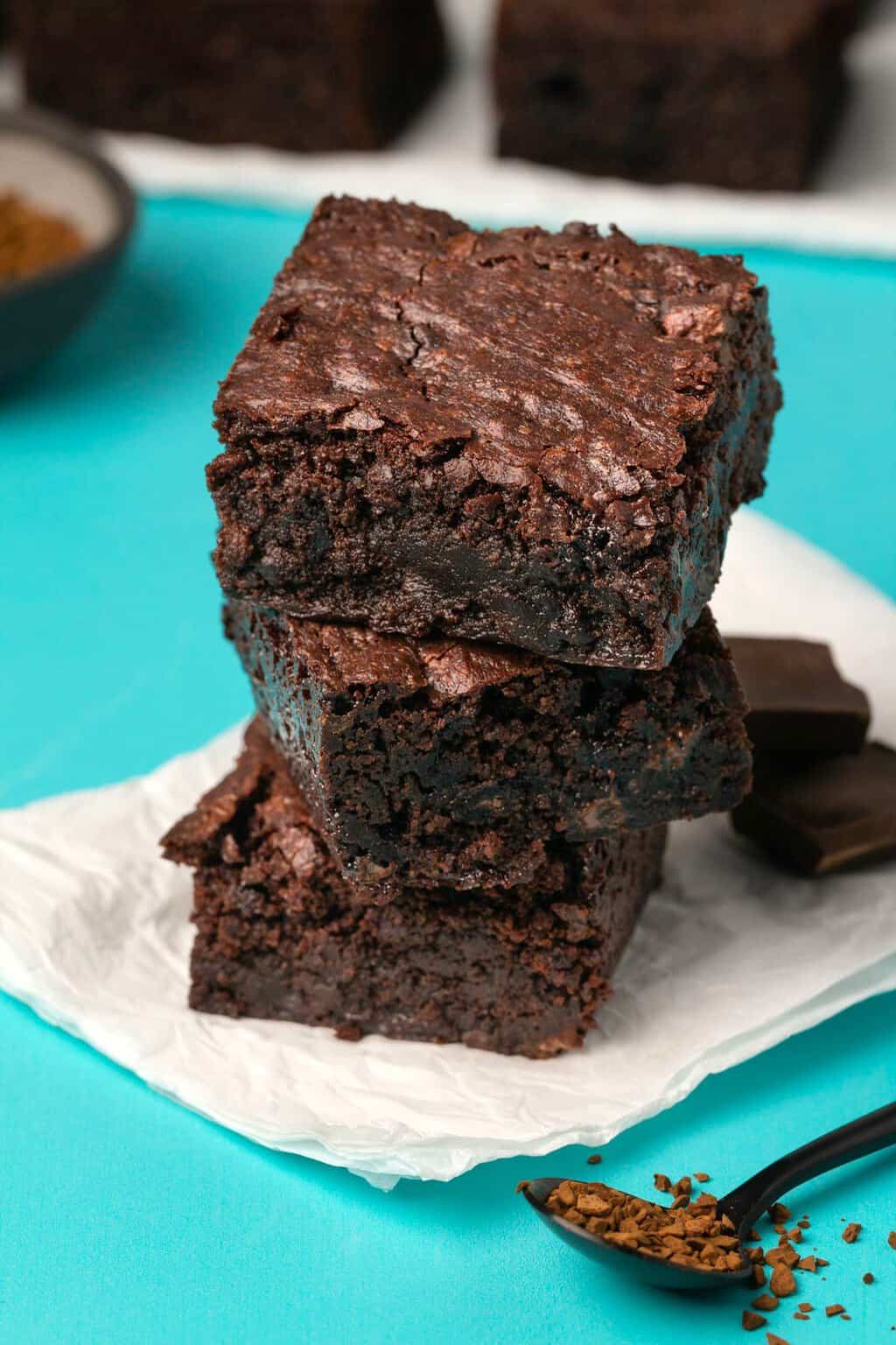 Brownies sans gluten végétaliens en pile sur du papier sulfurisé blanc.