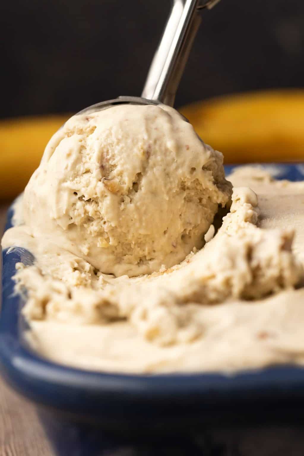 Glace végétalienne à la banane dans un plat en céramique bleu avec une cuillère à crème glacée.