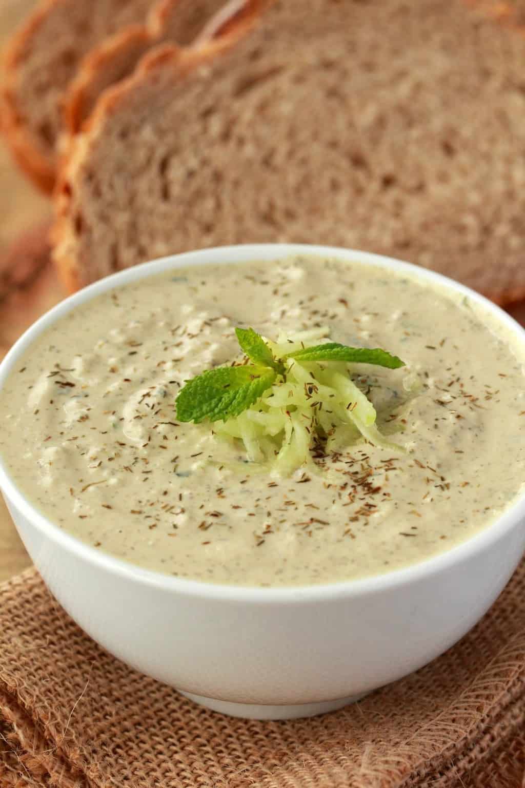 Tzatziki végétalien dans un bol blanc avec du pain de mie en arrière-plan.