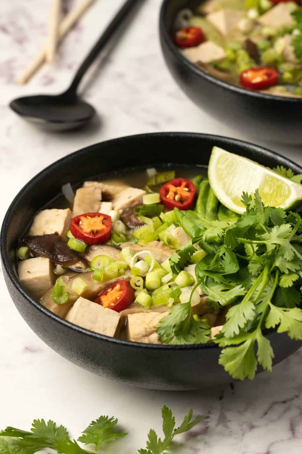 Pho végétalien au citron vert frais et aux herbes dans un bol noir. 