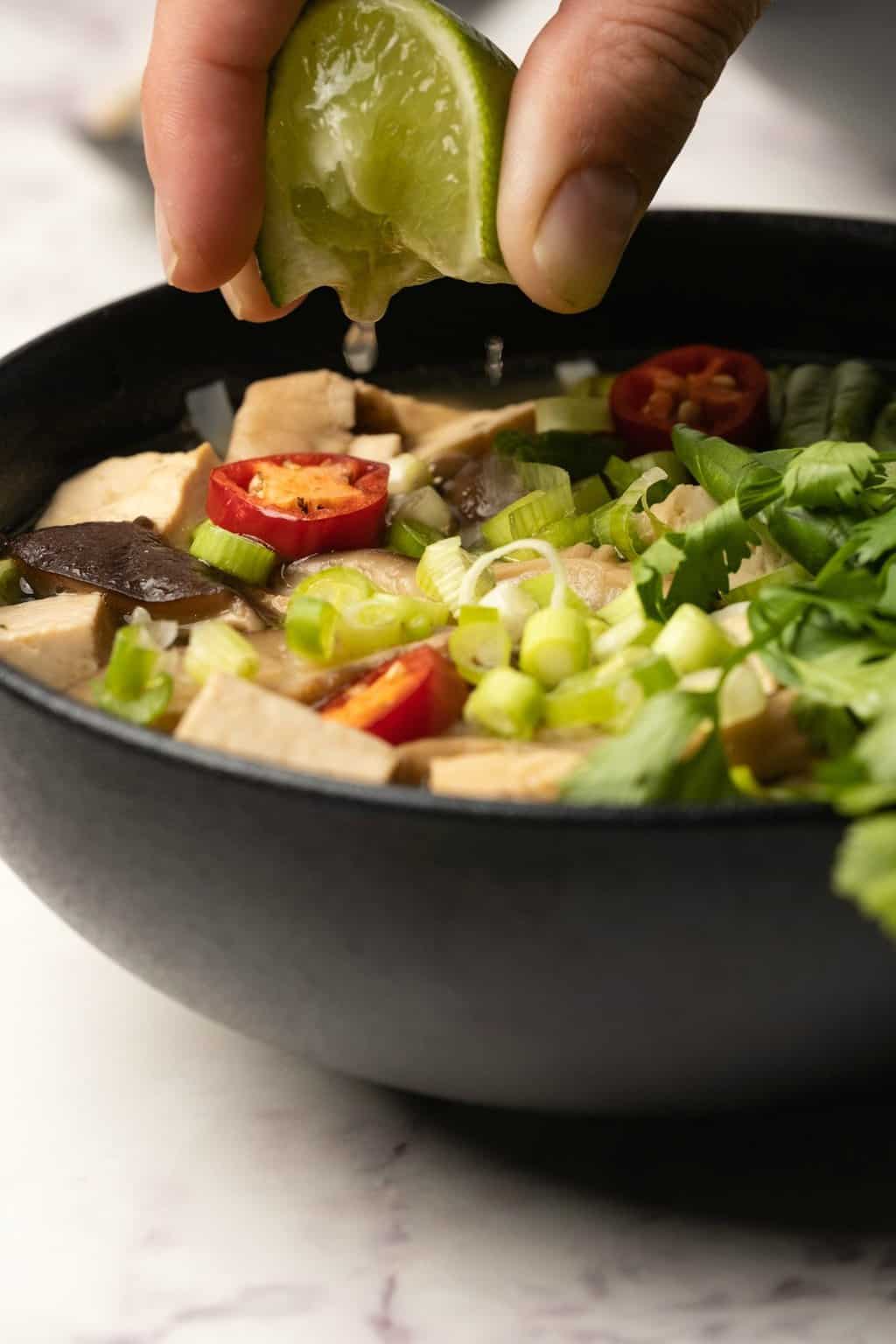 Presser la lime fraîche sur un bol de pho végétalien. 