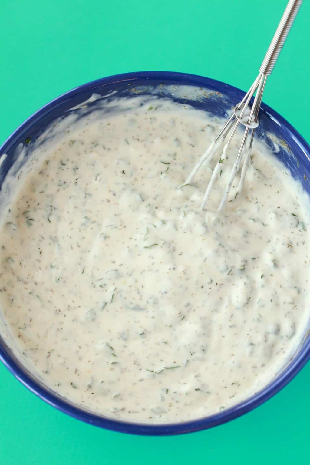 Vinaigrette végétalienne fraîchement mélangée dans un bol bleu avec un fouet. 