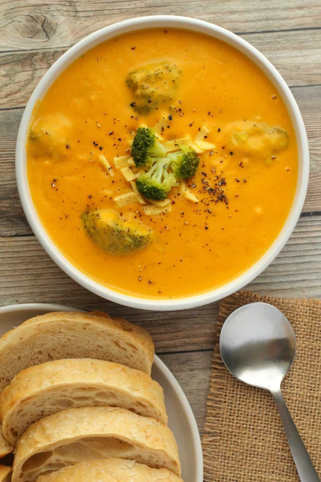 Soupe végétarienne au brocoli garnie de morceaux de brocoli et de fromage râpé dans un bol blanc. 