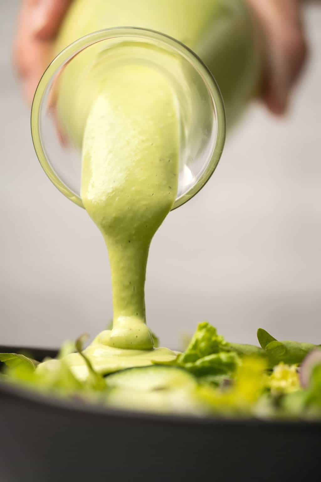 Vinaigrette aux noix de cajou versant sur une salade verte. 