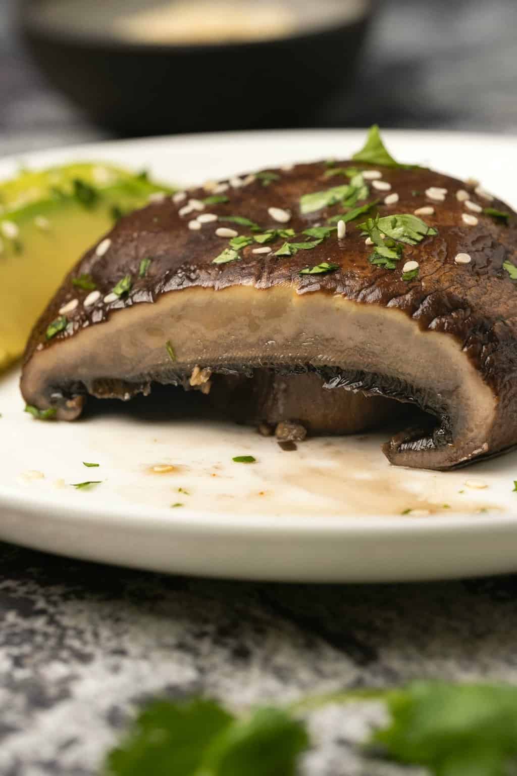 Champignon portobello tranché sur une plaque blanche avec avocat. 