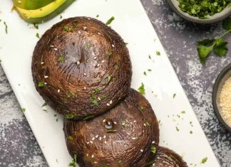 Champignons Portobello au four – Loving It Vegan Champignons portobello au four saupoudrés de coriandre hachée et de graines de sésame sur une plaque blanche.