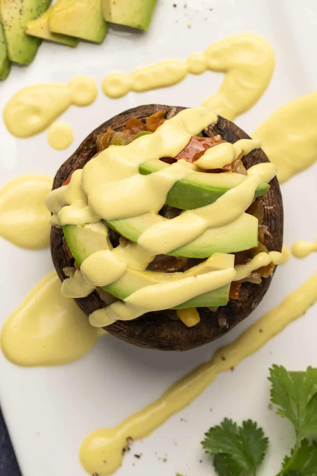 Sauce hollandaise végétalienne arrosée d'une pile de champignons et de légumes. 