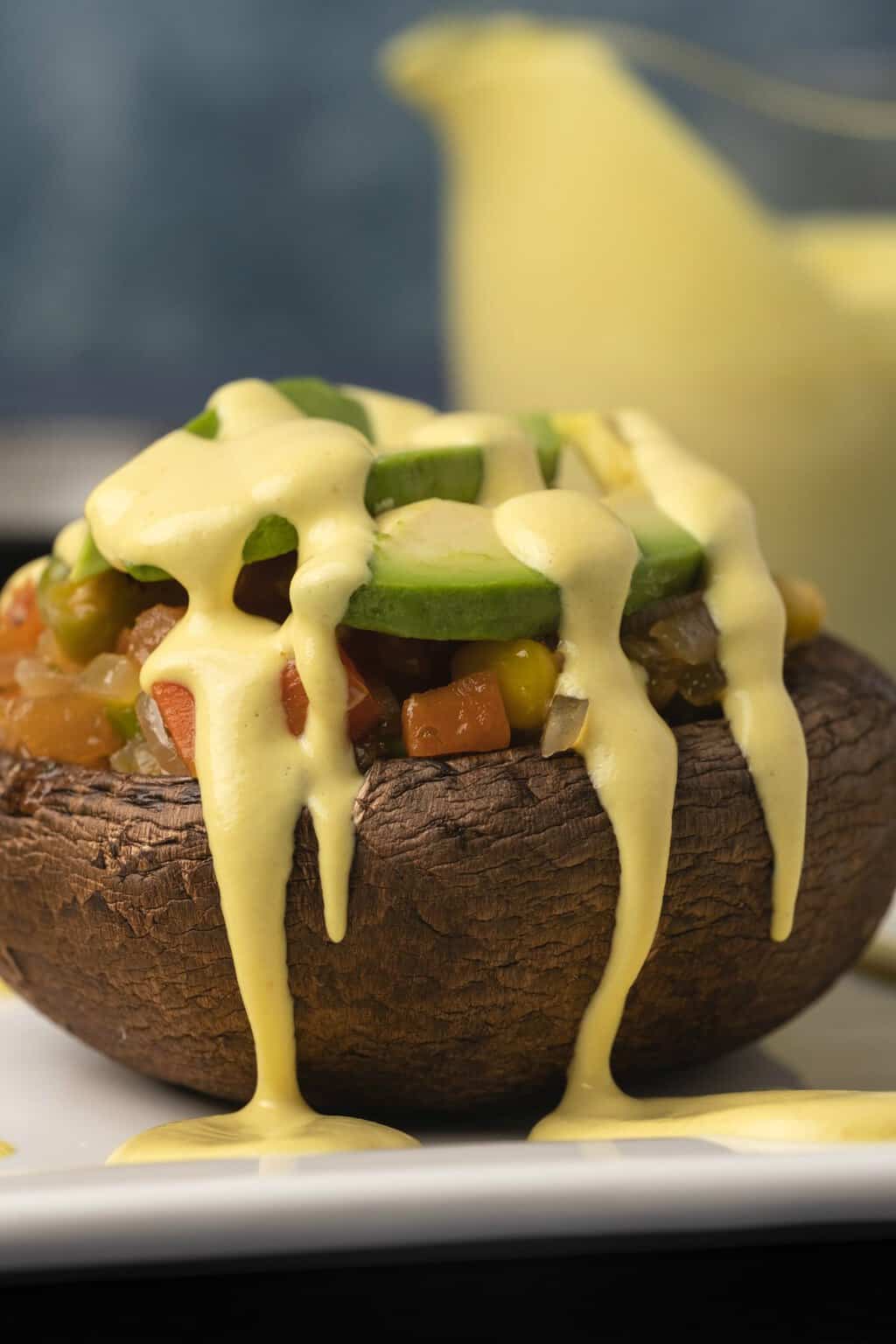 Sauce hollandaise végétalienne arrosée d'une pile de champignons et de légumes.