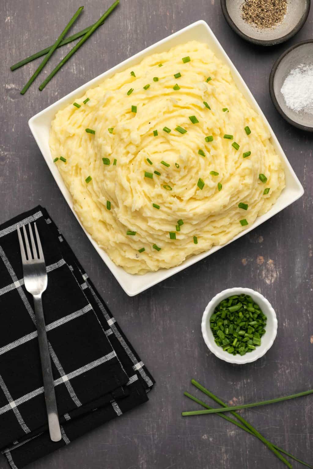 Purée de pommes de terre végétalienne garnie de ciboulette hachée dans un plat blanc. 