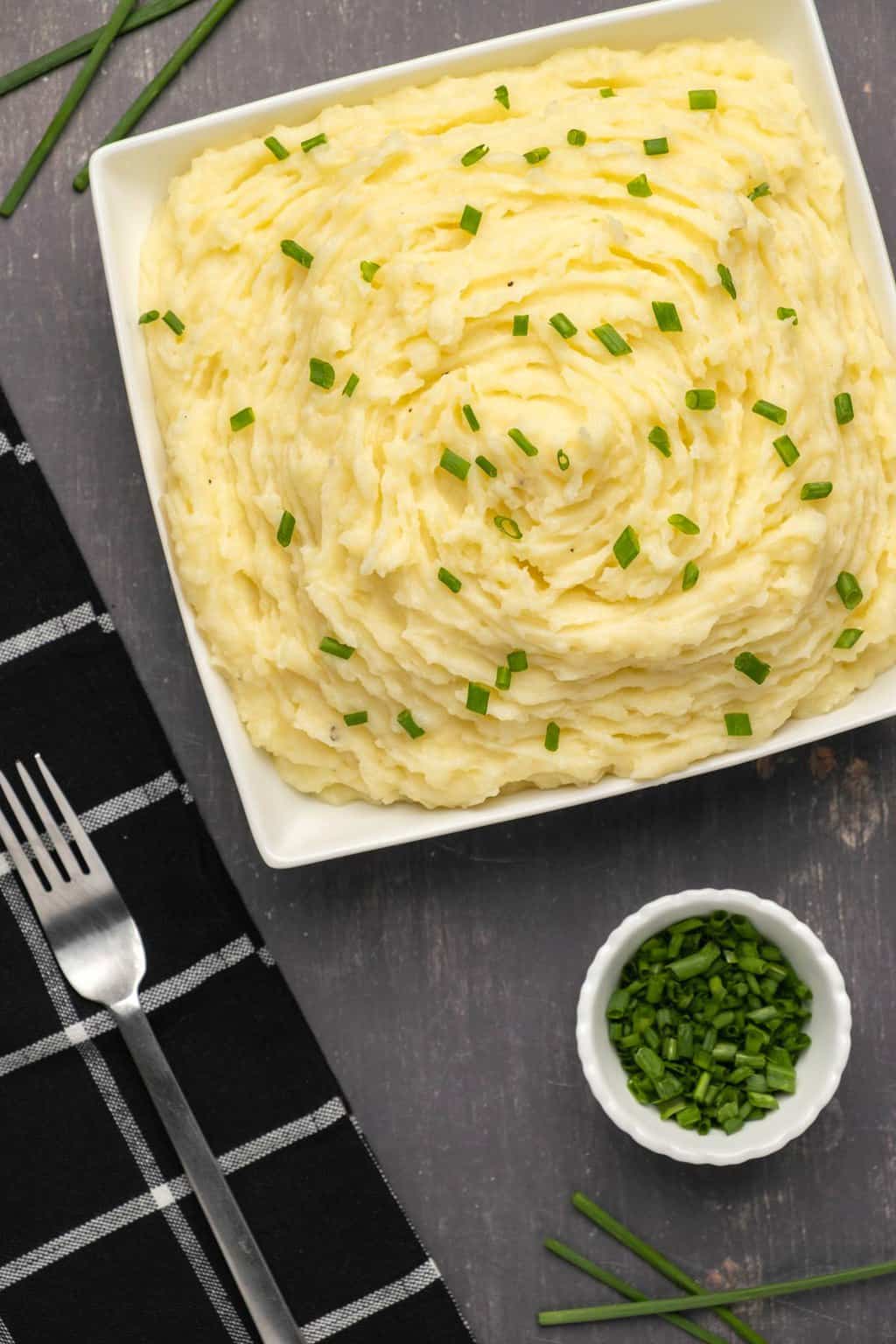 Purée de pommes de terre végétalienne garnie de ciboulette hachée dans un plat carré blanc. 