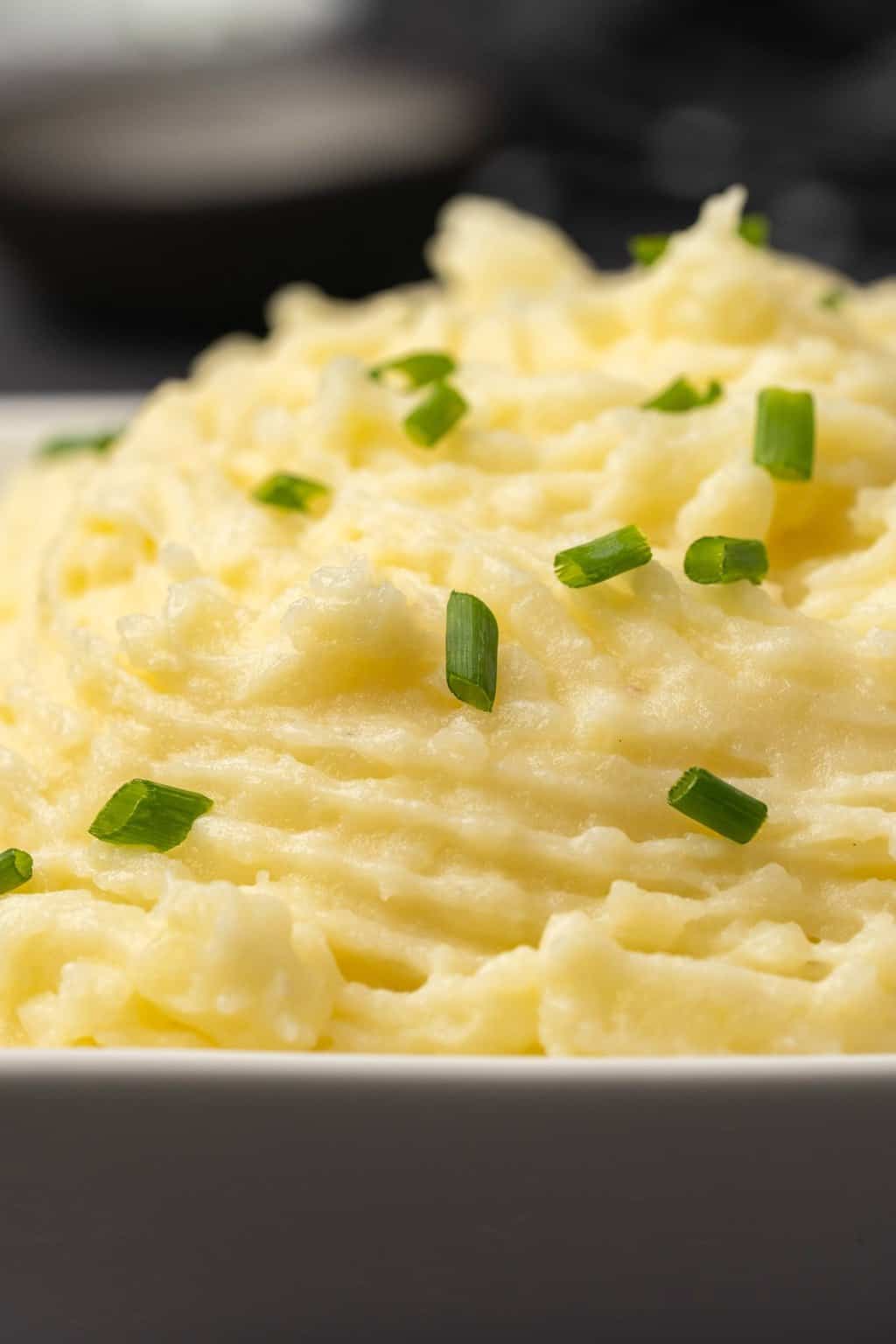Purée de pommes de terre végétalienne avec ciboulette hachée dans un plat blanc. 