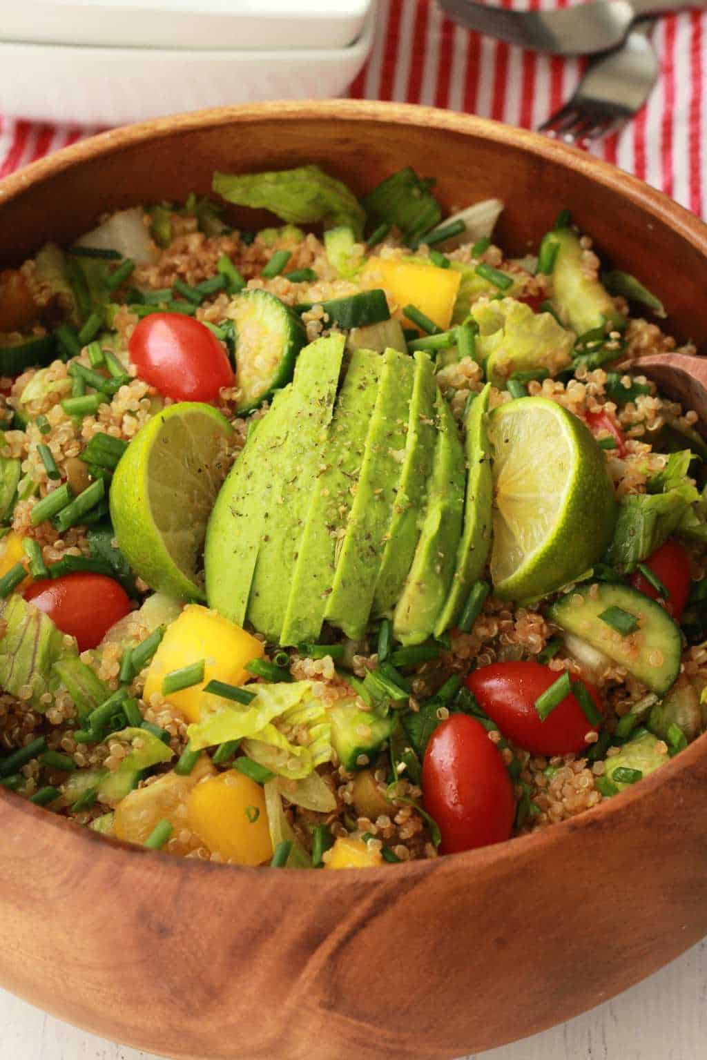 Salade de quinoa végétalienne garnie d'avocat tranché dans un saladier en bois. 