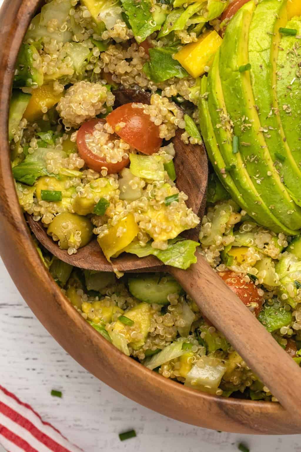 Salade de quinoa végétalienne dans un saladier en bois avec une cuillère à salade. 