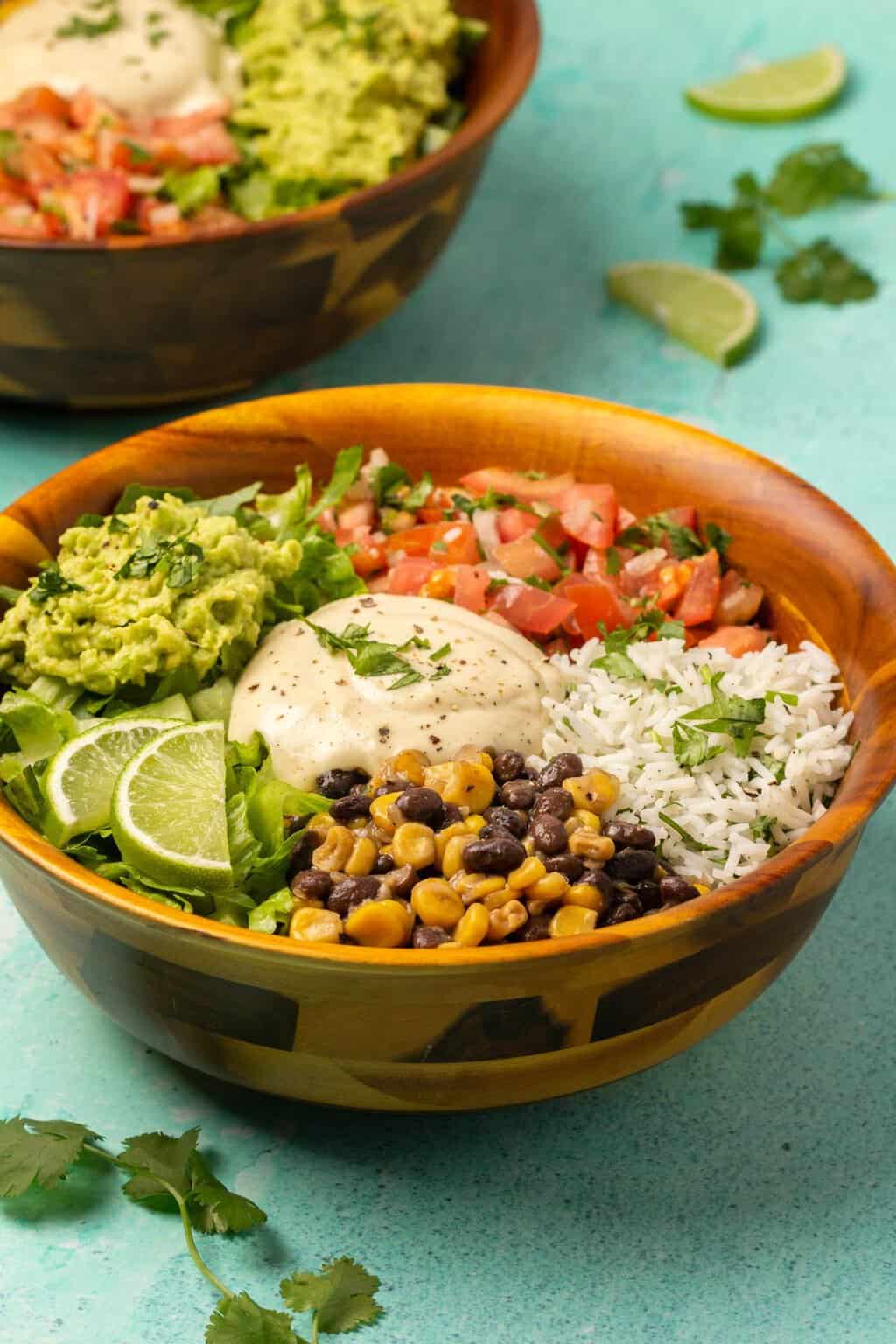 Bols de burrito végétaliens garnis de coriandre hachée et de tranches de citron vert frais.