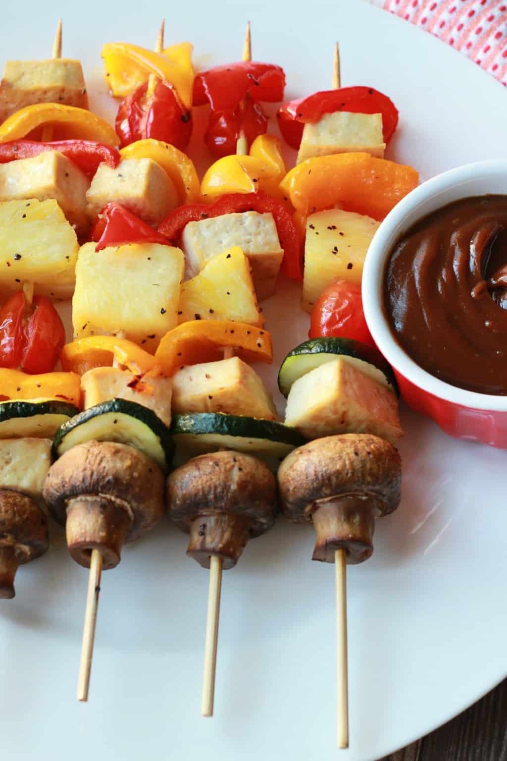 Brochettes de légumes sur une plaque blanche avec un bol de sauce trempette.