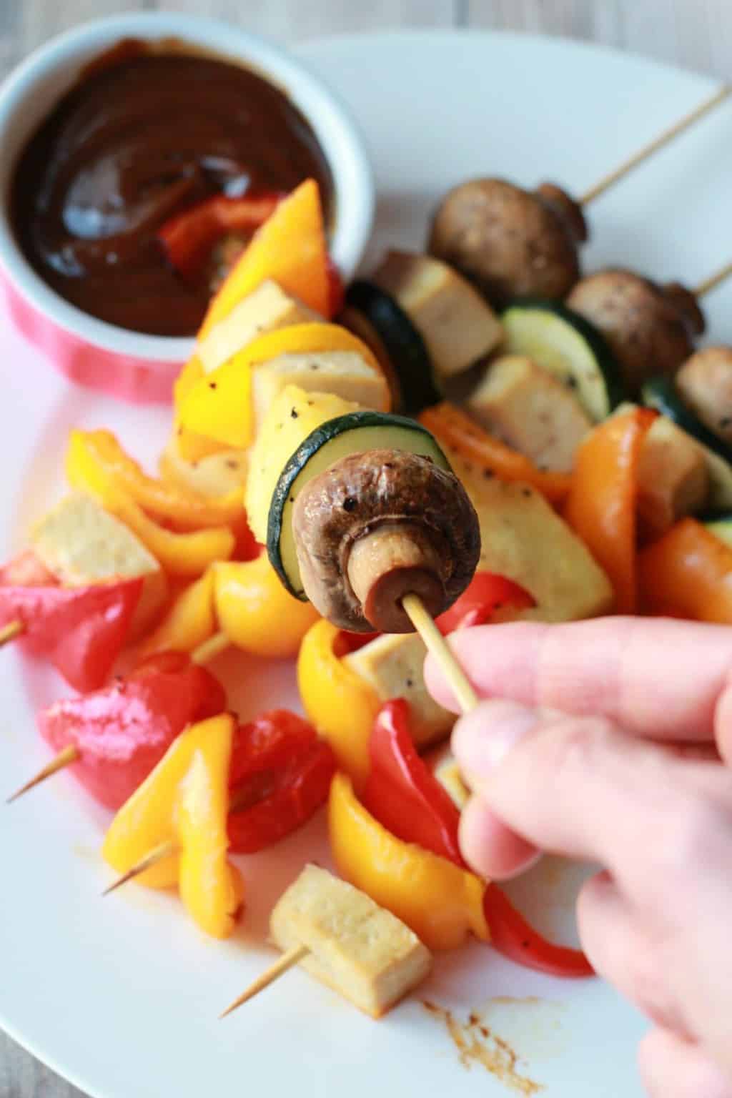 Tenant une brochette de légumes.