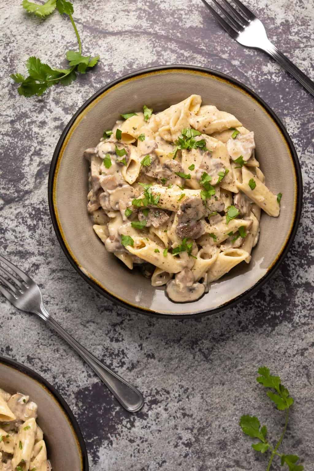 Pâtes aux champignons végétaliennes garnies de coriandre hachée dans un bol en pierre.