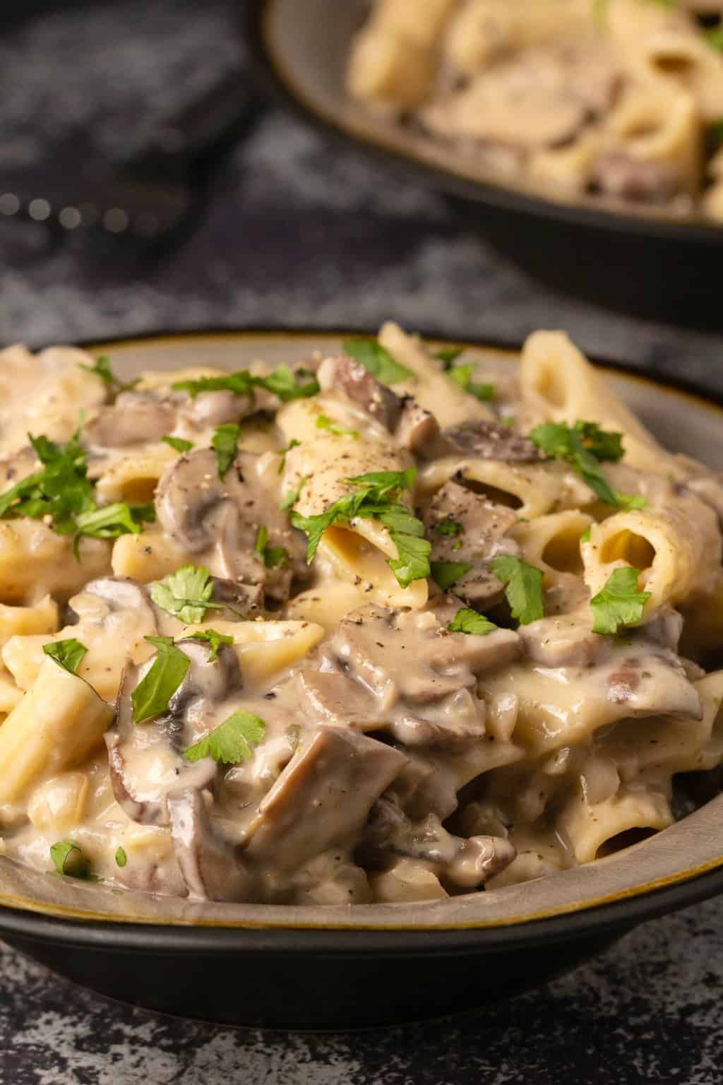 Pâtes végétaliennes aux champignons garnies de coriandre hachée et de poivre noir.