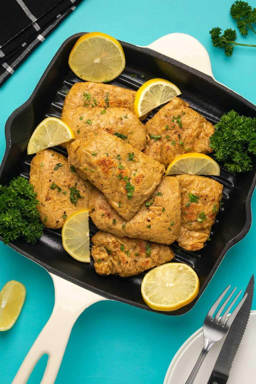 Filets de poulet végétaliens avec persil frais et tranches de citron dans une poêle.