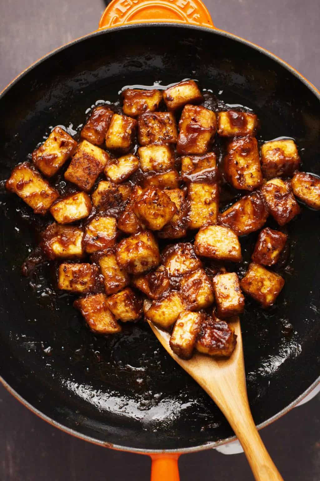 Le tofu du général Tso dans une poêle avec une cuillère en bois. 