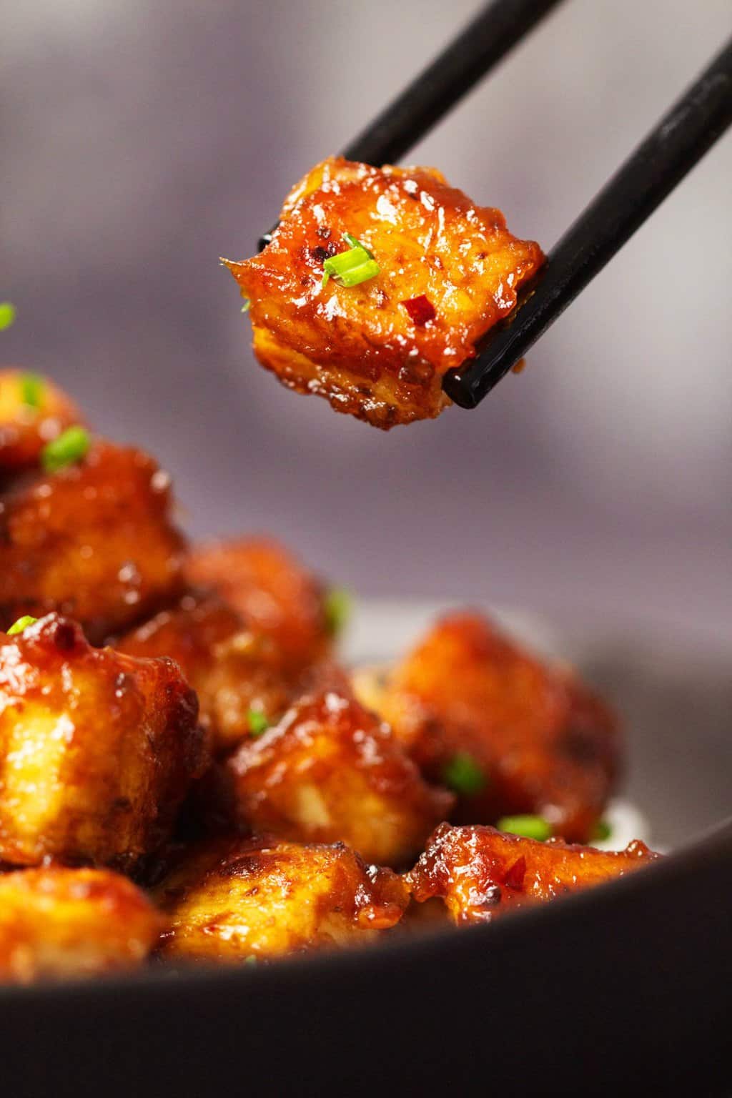 Le tofu du général Tso dans un bol noir avec des baguettes. 